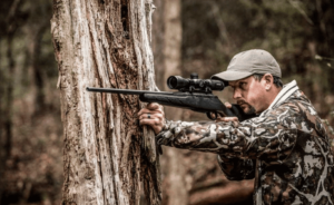 man shooting the Nightforce SHV 3-10x42mm Scope in the woods