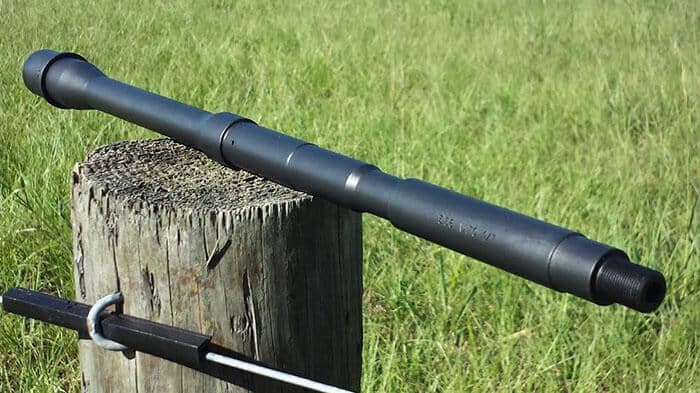 Two lined AR 15 barrels resting on a wooden stump outdoors