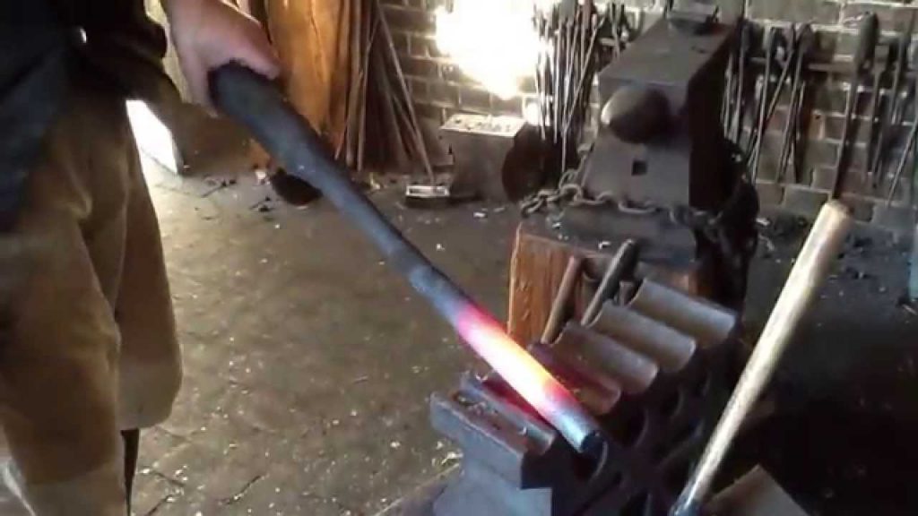 Man forging the barrel of an AR15 in his work shed red hot