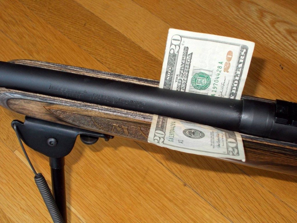 Close up of a free floating rifle barrel with dollar slid underneath it